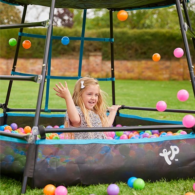 A girl enjoys playing outside, in a ball pool under tptoys climbing frame